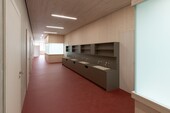 Hallway in school building with red floor and wooden ceilings